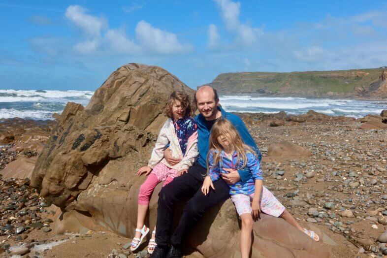 James, Lydia and Georgie sitting on a rock at the beach